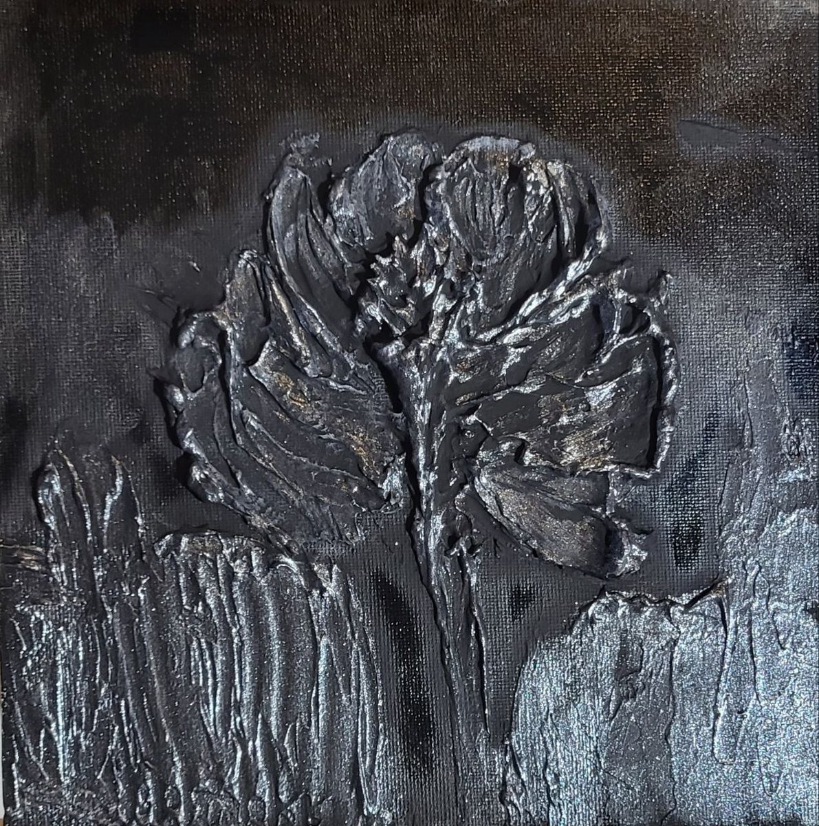 Sculpted silver-white bloom rising out of black, its petals in high relief
